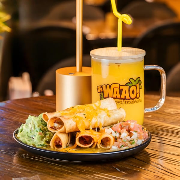 A plate of cheesy taquitos with guacamole and salsa, next to a WAAO! juice drink.